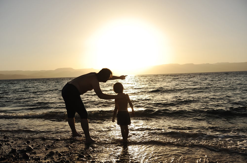 Happy child with his father at sea together. Sunset