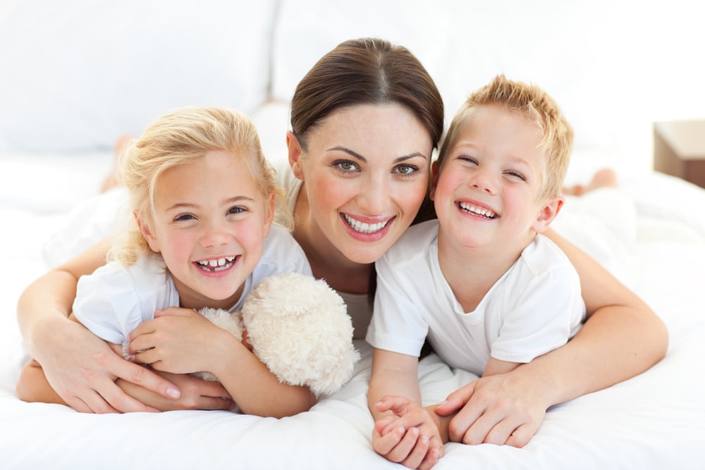 Portrait of a happy mother and her children lying on a bed